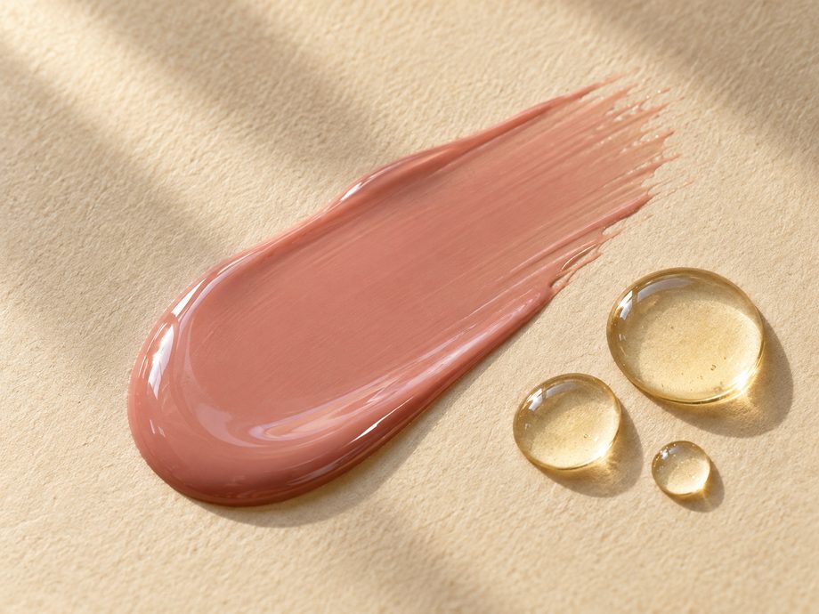 Swatch of blush-pink nail polish with plant-oil droplets